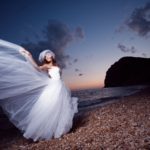 Bride posing showing her wedding dress on sunset beach